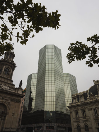 Panorama view of historical building and modern architecture framed by trees on Plaza de Armas of...