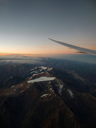 Panorama view of sunset in snowcapped andes mountains with airplane wing from airplane window seat landing in Santiago de Chile South Americaの写真素材