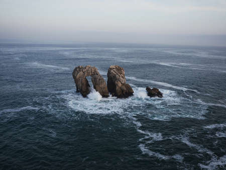 Panorama view of Urro del Manzano rock formation sea stack natural arch bridge in Liencres Arnia...