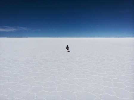 One isolated male tourist enjoying endless boundless infinite vastness width expanse of white salt...