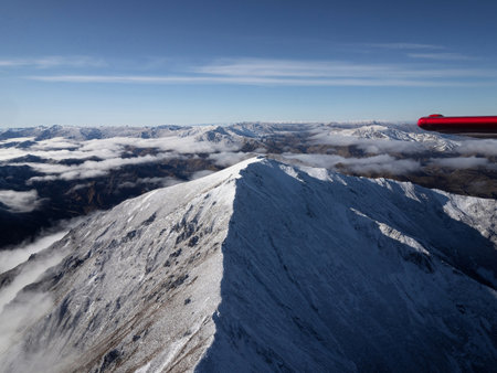 Aerial alpine mountain landscape panorama with airplane wing, white snow capped peaks of the Southern Alps, Otago Southland South Island New Zealandの写真素材