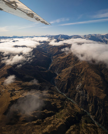 Aerial alpine mountain landscape panorama with airplane wing, above meander river in Southern Alps valley, Otago Southland South Island New Zealandの写真素材