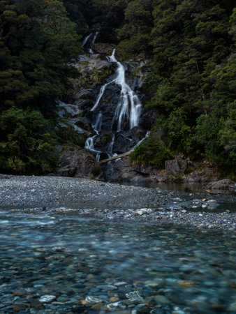 Fantail Falls waterfall creek stream flowing into crystal clear blue turquoise Haast River near Haast Pass in Mount Aspiring National Park Westland District South Island New Zealandの写真素材