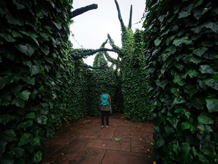 A young woman strolling through giant oversized green artificial bush trees playful dreamworld...
