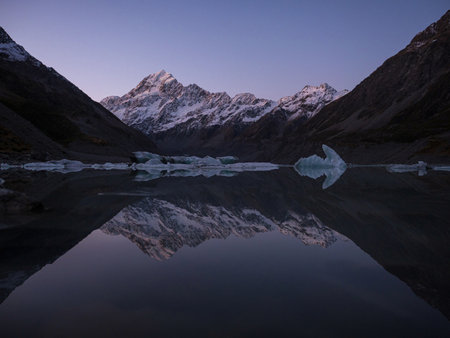 Mirror pond reflection tarn view of Mount Cook Aoraki from Hooker Lake with floating icebergs, snow covered alpine mountain landscape of Southern Alps in Canterbury South Island New Zealandの写真素材