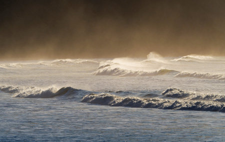 Kaiaua Bay beach golden hour sunrise morning sun soft light, Pacific Ocean wave crest wind mist haze near Gisborne North Island New Zealandの写真素材