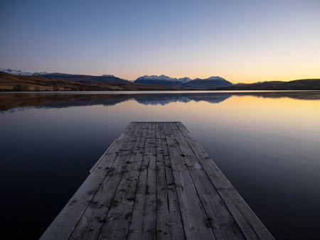 Idyllic calm serene tranquil Lake Alexandrina boat jetty pier wooden bridge early morning golden hour sunrise mountain landscape nature panorama near Tekapo Canterbury South Island New Zealandの写真素材