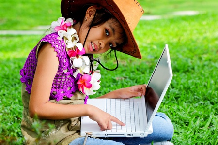 A girl wearing a cowboy hat with laptop in the garden