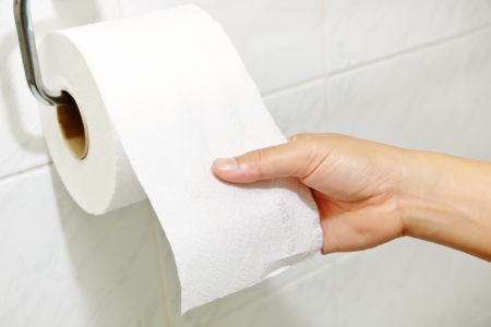 Woman hand holding the roll of toilet paperの写真素材