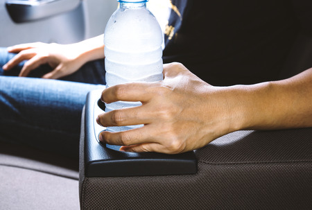 Woman hand hold drinking water bottle on cup holder in carの写真素材