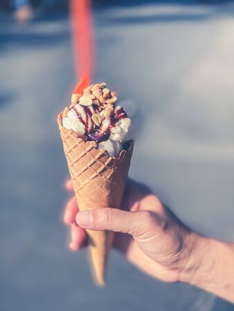 Woman hand holding ice cream cone with chocolate and nuts sweet food backgrounds