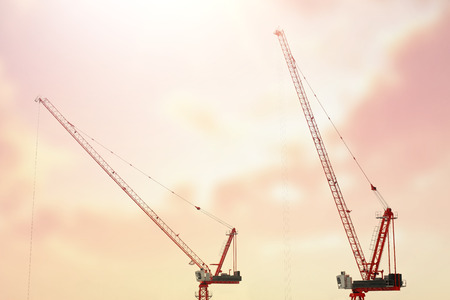 Large construction site including several cranes working on a building complex, with clear blue sky and the sun. Crane construction site / top view.の写真素材