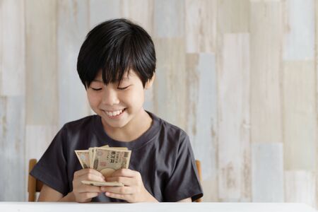 Elementary school boy counting 10,000 yen billsの写真素材