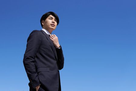 Japanese male businessman in blue sky backgroundの写真素材