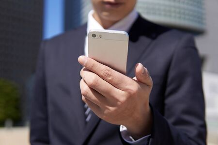 Japanese male businessman who operates smartphone