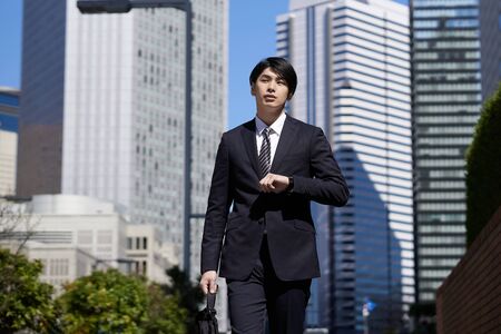 Japanese male businessman walking in the office districtの写真素材