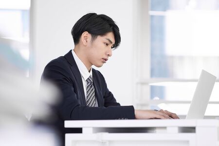 Japanese male businessman who concentrates and works on a laptopの写真素材