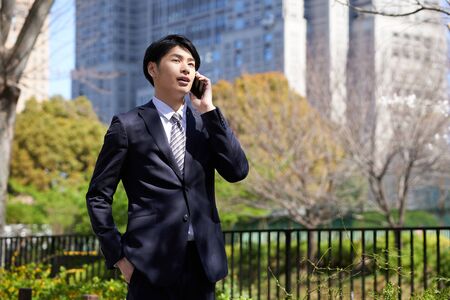 Japanese male businessman with smartphone in the background of the buildingの写真素材