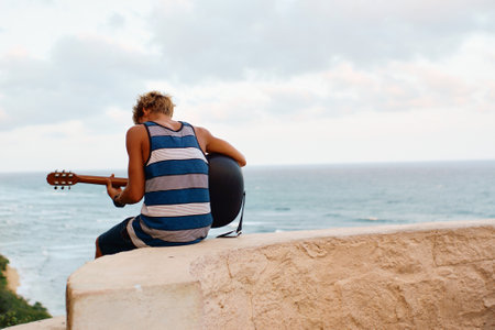 a man playing the guitar by the sea