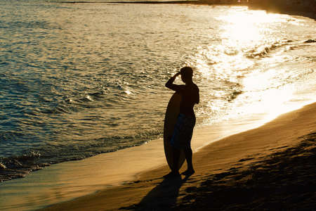 Surfers illuminated by the sunset at Waikiki Beach, Hawaii