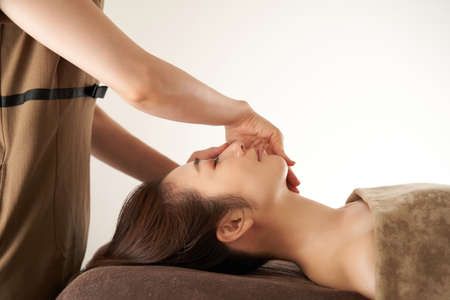 Japanese woman receiving facial massage at beauty salonの写真素材