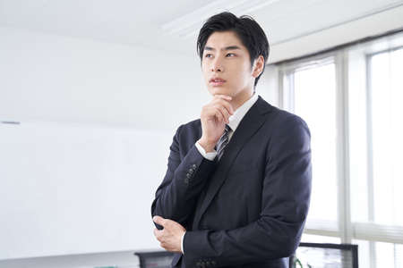 A Japanese male businessman thinking in a conference roomの写真素材
