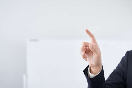 Japanese male businessman pointing at a conference room for text synthesisの写真素材