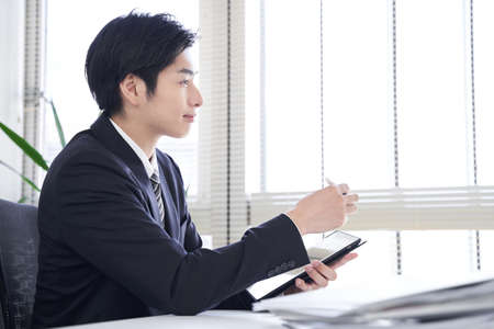 Japanese male businessmen interviewing using a tablet in the officeの写真素材
