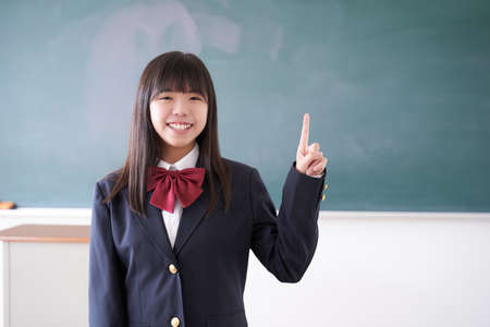 Japanese girl junior high school student pointing her finger in the classroomの写真素材