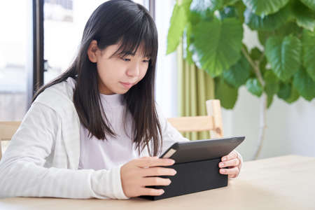 Japanese girls junior high school students looking at a tablet in the living room