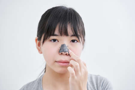 Japanese female junior high school student applying nose packの写真素材