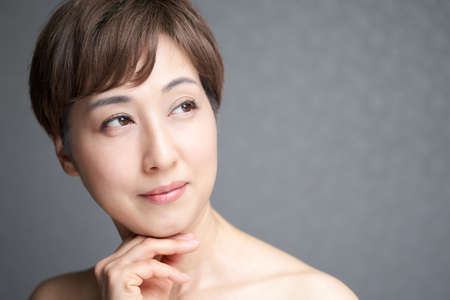 a middle-old Japanese woman who looks away and put her hand on her chin