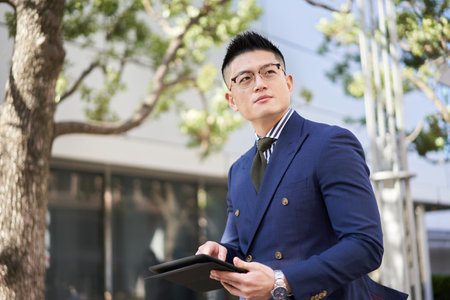 Asian businessman researching on tablet outsideの写真素材