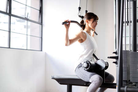 Asian woman back rat pull-down at training gym