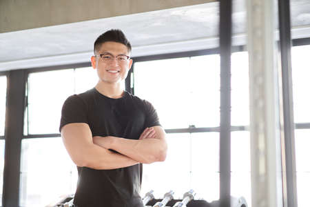 Asian male trainer with smile and arms folded