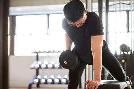 Asian man playing one-hand bentover row in training gymの写真素材