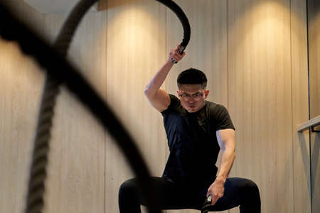 Asian man training on battle ropes