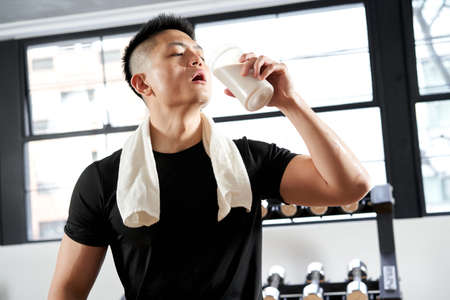 Asian man drinking protein after trainingの写真素材