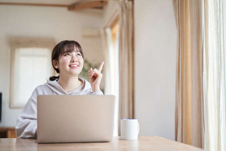 Asian woman smiling and operating computer in living room