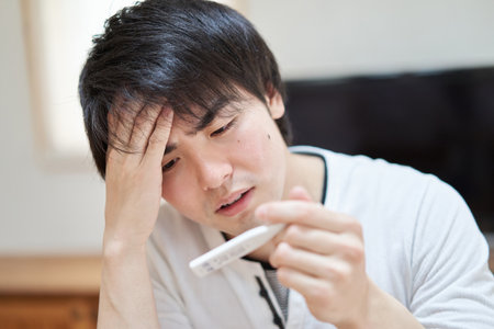 Asian man measuring heat with thermometer