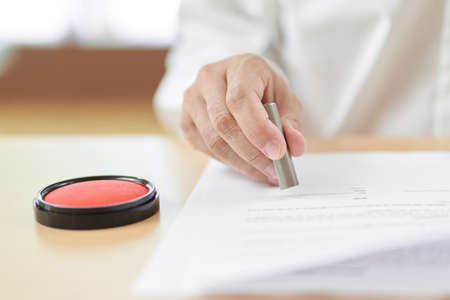 The hand of the elderly who presses the seal on the contract