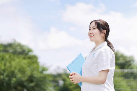 Female nurse standing with a smile on a blue sky backgroundの写真素材
