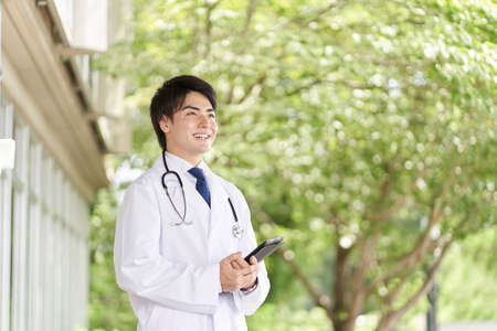 Doctor standing with a smile on a green backgroundの写真素材
