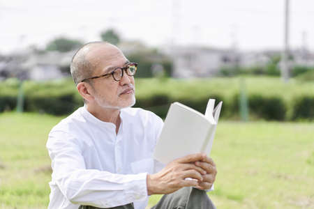 Elderly Asian Male Reading Outside