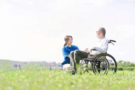 Elderly and caregivers having a conversation on the lawnの写真素材