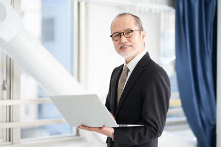 A man in a managerial position at a construction company operating a personal computerの写真素材