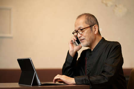 The owner of a restaurant who makes a phone call while looking at a computer