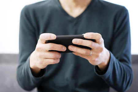 Asian man playing games on his smartphoneの写真素材