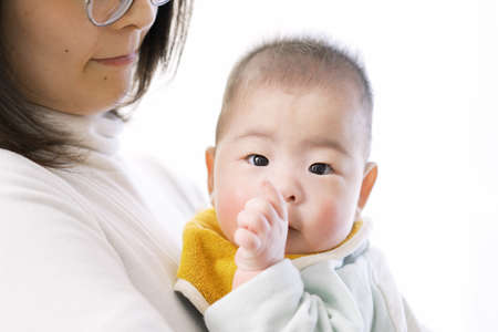 Asian baby hugged and sucking fingersの写真素材
