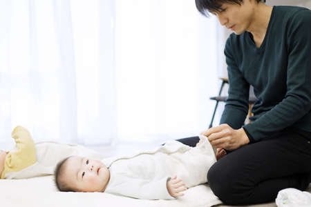 Asian dad changing baby clothes